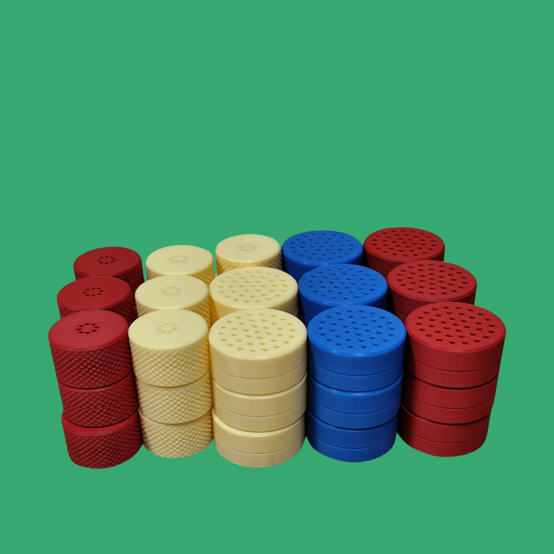 Colored stackable discs in red, yellow, and blue arranged in groups against a green background.